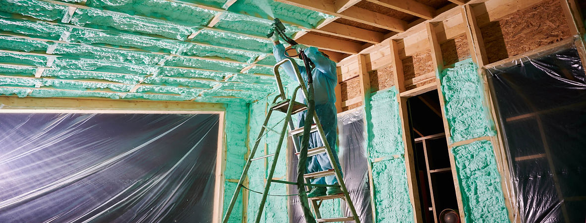A man standing on a ladder in a room with insulation.