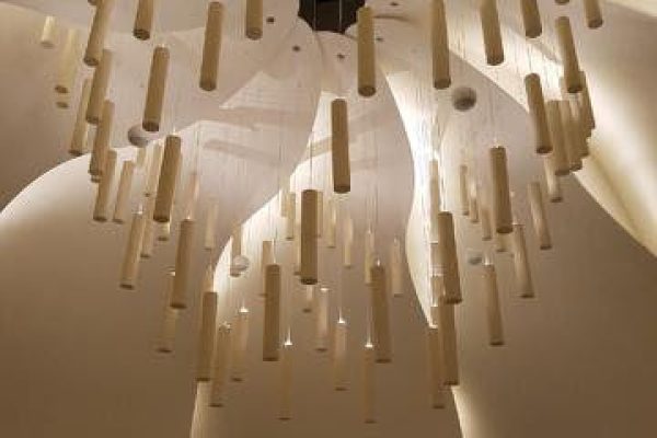 A grand chandelier with numerous lights hanging in an elegant building.